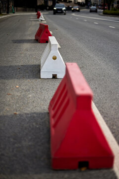 Traffic barriers, road safety, construction zone, roadwork and temporary street closure in urban infrastructure, with red and white barriers separating vehicles from a protected roadside area