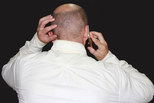Pensativo con tel&eacute;fono, camisa blanca y fondo negro hombre calvo preocupado con m&oacute;vil black background estr&eacute;s y agobio con smartphone celular