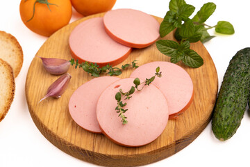 Sliced boiled sausage background closeup with fresh ham slices on wooden cutting board, organic pork meat product breakfast appetizer with white bread, green cucumber, garlic cloves and yellow tomatoe © Inna Nikitina