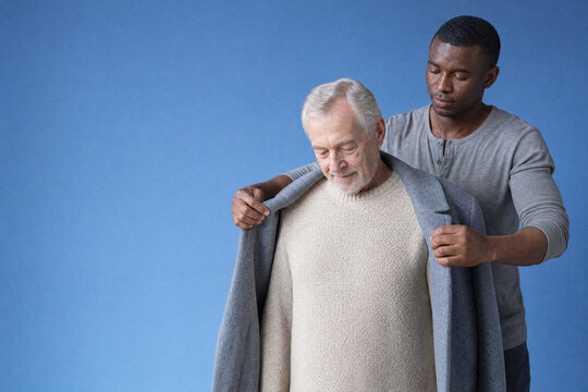 Home caregiver helping an older man into his winter coat