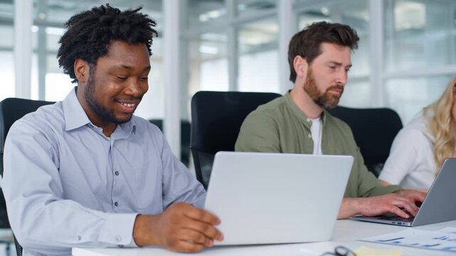 Business team three diversity business workers typing computers African American businessman showing laptop good result to Caucasian colleagues amazed celebrate supporting happy in office coworking