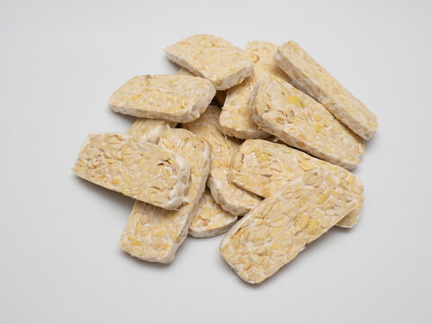 Sliced tempeh or tempe, a traditional Indonesian food made from whole soybeans that are fermented and pressed into a dense, firm cake, isolated in a white background