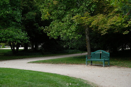 Green wooden bench on path in shady park