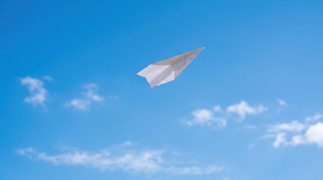 White paper airplane flying high in clear blue sky with soft clouds, symbolizing freedom, creativity, dreams, travel, communication, simple childhood joy, hope, future
