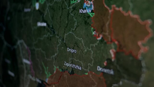 Glowing Ukraine map on dark green digital screen showing highlighted regions and city lights for Kharkiv, Dnipro, and Zaporizhzhia