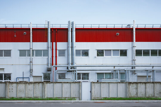 Modern industrial building exterior with ventilation pipes and metal wall cladding. Commercial warehouse facade, manufacturing plant infrastructure and industrial real estate concept.