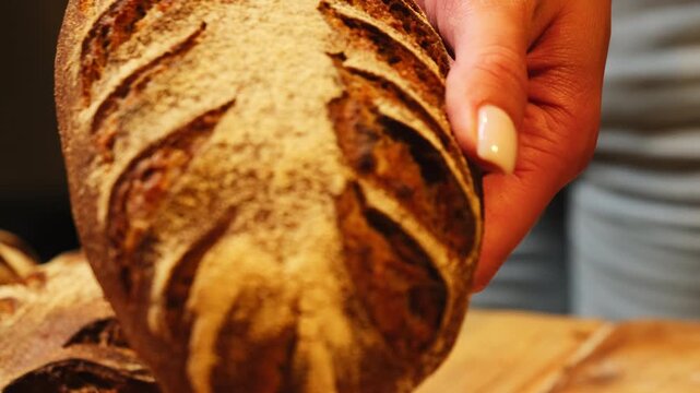 Young woman shows rye loaf with beautiful decorative design. Beautifully textured crust of bread decorated with delicate flour patterns