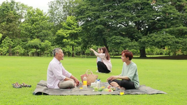 child runs with mother in summer field, small child playing on the lawn. spending time with father in the park. Happy Asian family having fun time on picnic at city nature park, outdoor activitie