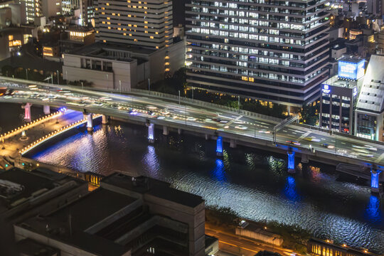 超高層ビルから見下ろす都市高速道路の光跡とリバーサイド夜景