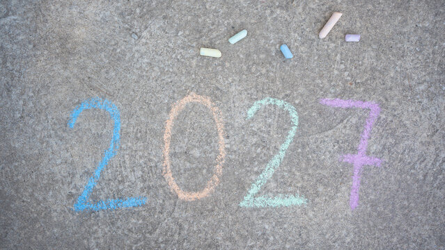 Chalk drawing 2027 numbers on asphalt representing future