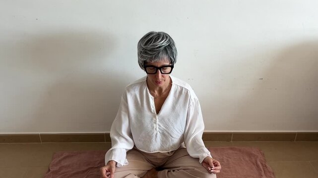 Mujer haciendo ejercicios de respiraci&oacute;n para menopausia en suelo