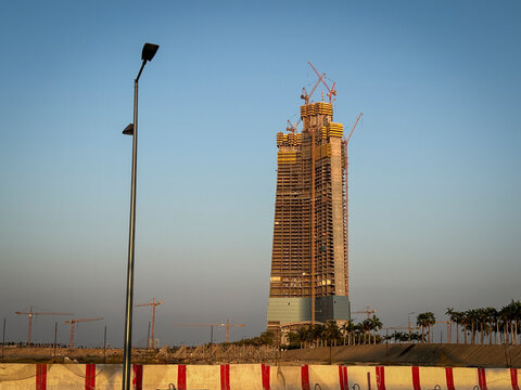 A red-and-white barrier lines the roadside as the unfinished Kingdom Tower rises in the distance, Makkah, Jeddah, Saudi Arabia