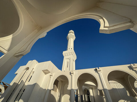 White arches frame the minaret of the Al-Rahmah Mosque against a clear blue sky, Makkah, Jeddah, Saudi Arabia