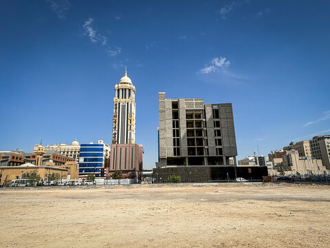 An ornate domed tower rises beside an unfinished building above an empty lot, Riyadh, Riyadh, Saudi Arabia