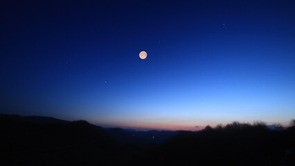 Full Moon, stars and planets above landscape silhouettes. © astrosystem