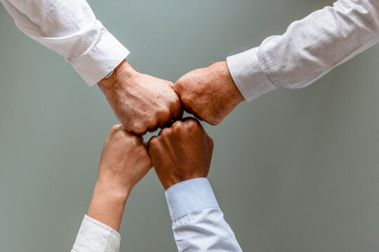 Three hands of diverse individuals fist-bumping in unity.
