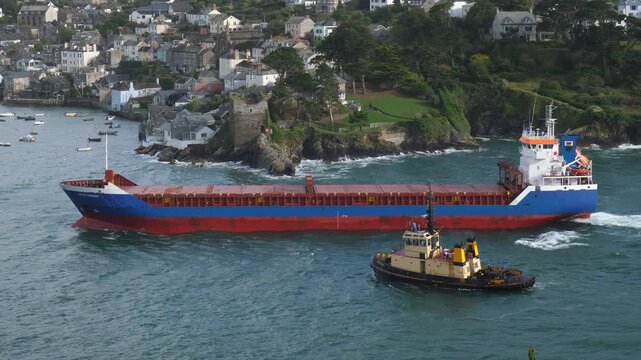China Clay ship entering  Fowey Harbour, accompanied by tug. Fowey is an important export port for China Clay (kaolin) mined in Cornwall, UK. This unladen ship is entering Fowey harbour 