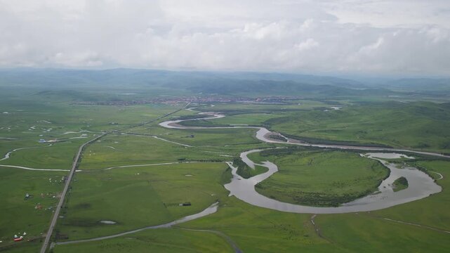 High-Angle Aerial Panoramic View of Meandering Baihe River and Waqie Town in Hongyuan, Aba, Sichuan: Winding Water System, Sea of Clouds, Green Grassland and Horizon Background