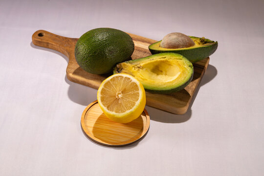 avocado on a cutting board and a lemon on a stand