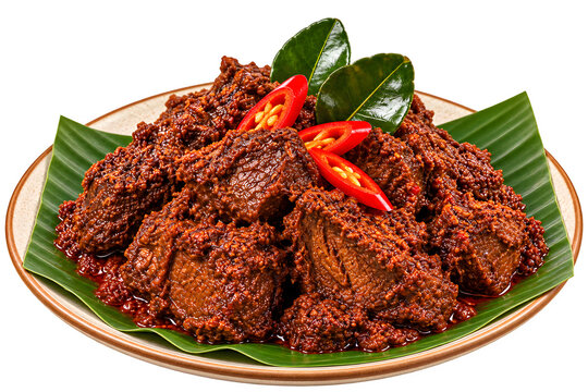 Traditional Indonesian beef rendang with rich spicy sauce, tender meat, red chili and aromatic herbs, beautifully served on a banana leaf-lined ceramic plate.