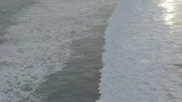 Surf lines approaching a wide sandy beach