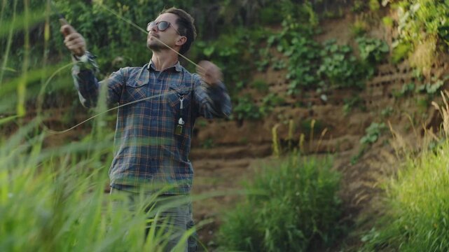 Young adult fisherman fly fishing on the small shallow river and casts