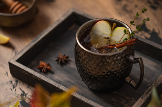 Apple cider in hammered copper mug with apple slices, autumn beverage