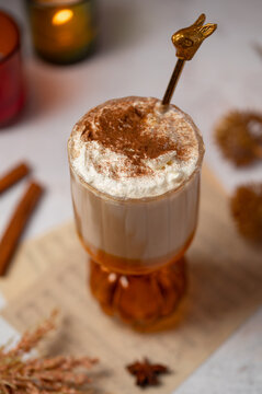 Autumn latte with whipped cream and cinnamon, candlelit cozy drink