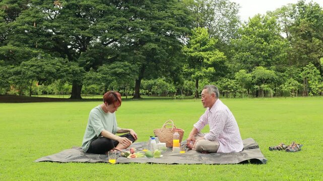 child runs with mother in summer field, small child playing on the lawn. spending time with father in the park. Happy Asian family having fun time on picnic at city nature park, outdoor activitie