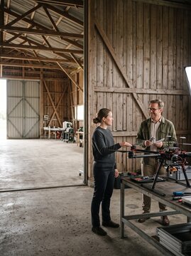 Two engineers inspecting and assembling a modern industrial hexacopter drone inside a spacious rustic wooden workshop