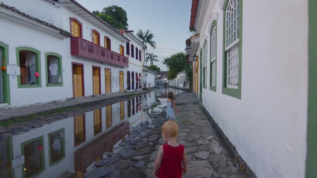 Tourists walk on the street of the colonial town of Paraty filled with water, Brazil