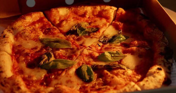 Freshly baked Neapolitan pizza in a delivery box. Close-up shot of artisanal Italian pizza in warm evening lighting