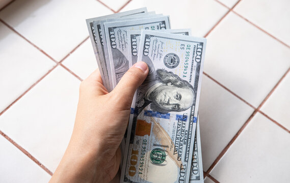 Hand holding US dollar banknotes, illustrating wealth, cash payments, financial transactions, corruption, bribery and money laundering