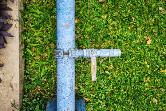 water pipeline with a steel valve and clamp installed over green grass, plumbing and water supply infrastructure concept.