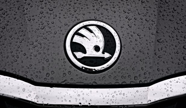 Neu-Ulm, Germany - September, 13, 2026: Close up of Skoda car logo on metallic surface with rain drops. Panoramic image. 