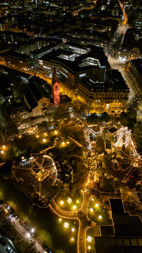 Vertical drone aerial view of Berner Sternenmarkt Christmas market illuminated at night in Bern, Switzerland