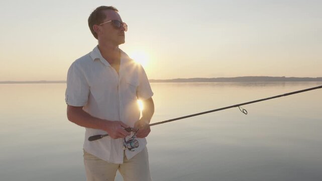 Young man fishing on the river during sunset and casts a lure