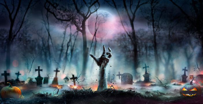 Halloween Zombie - Hands Rising Out Of A Cemetery In Forest At Night With Abstract Bokeh Lights And Defocused Background
