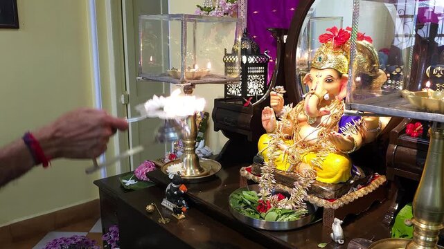 Devotee performing aarti in front of a decorated Lord Ganesha idol during Ganesh Chaturthi celebrations
