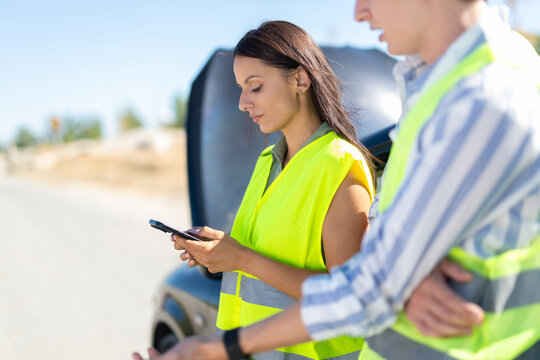Woman using smartphone for road assistance after car breakdown