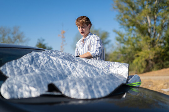 Man putting car sunshade for heat protection