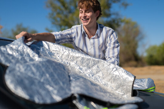 Young man placing sun shade on car windshield