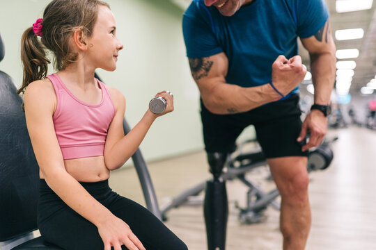 Daughter and father training at gym, showing strength