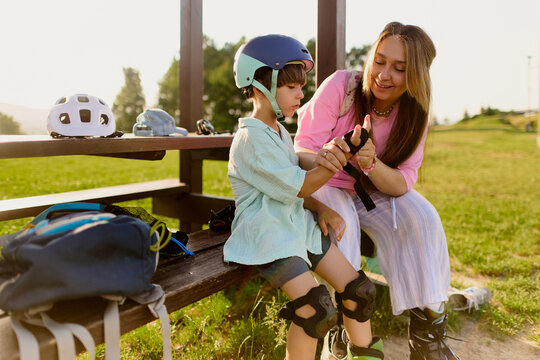 Mother Helping Son Put on Roller Skates in the Park
