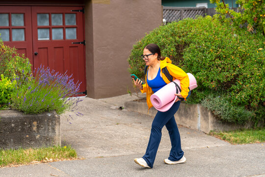 walking and talking on phone with yoga mat
