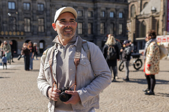 Confident Male Traveler Smiling at Amsterdam Plaza