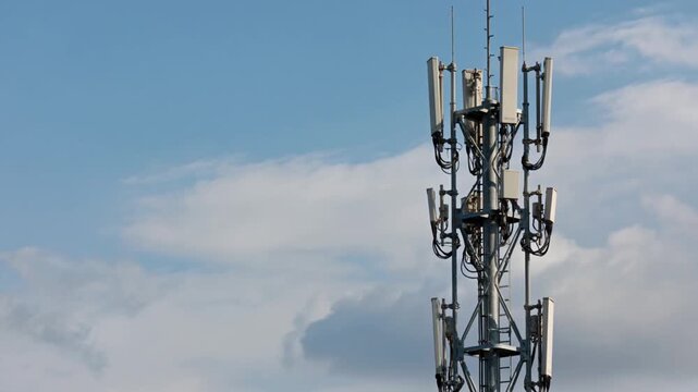 Mobile communication tower against a blue sky with clouds  