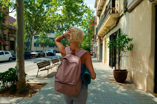 Walking on a City Street With a Backpack and Yoga Mat in Hand