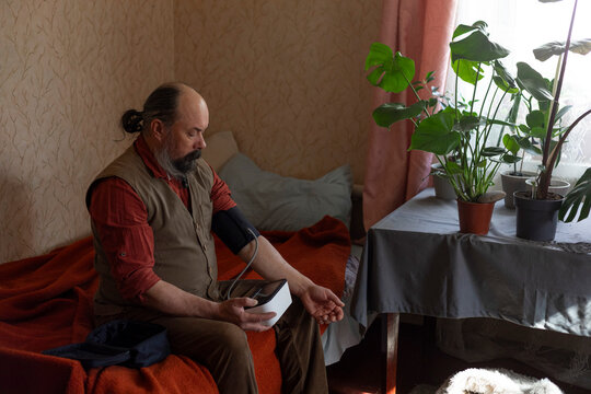 Mature man measuring blood pressure with a digital monitor at home