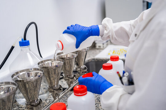 Laboratory Worker Pours Liquid Into Funnels During a Process